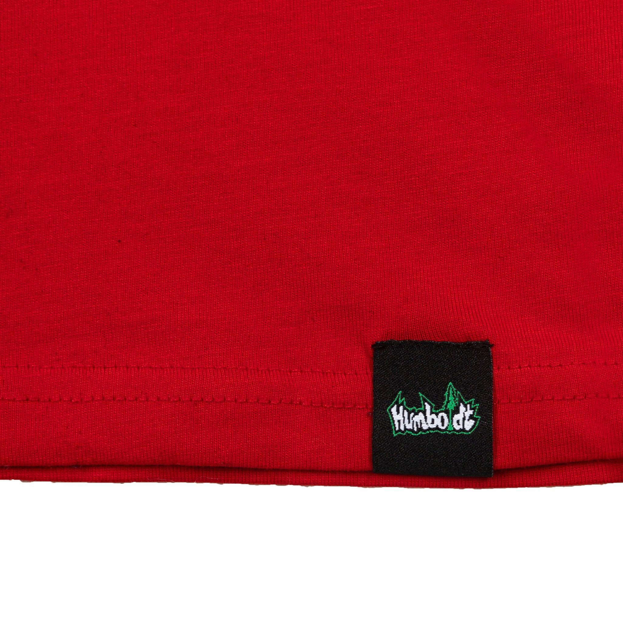 Red t-shirt hem with black woven label featuring green and white 'Humboldt' logo, showcasing quality apparel detail.