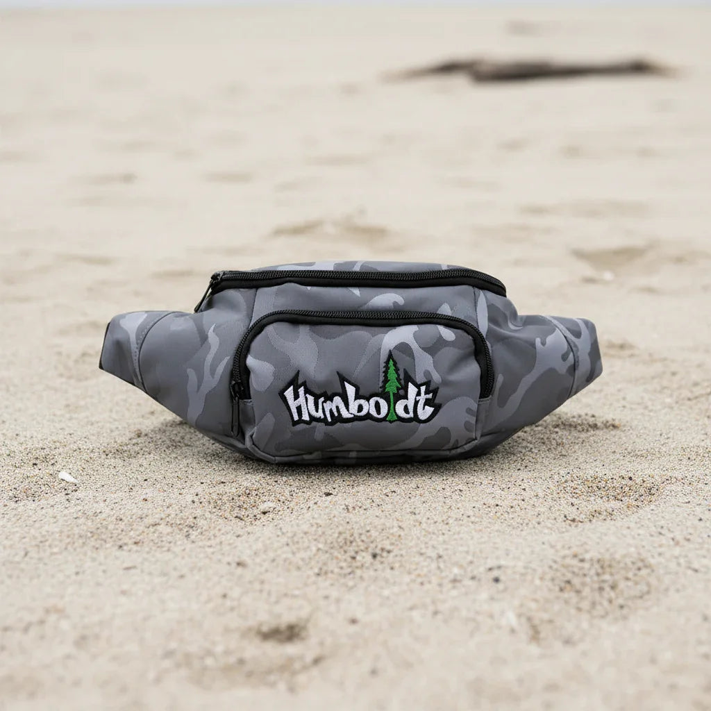 Gray camo fanny pack with Humboldt logo on sandy beach, outdoor streetwear accessory
