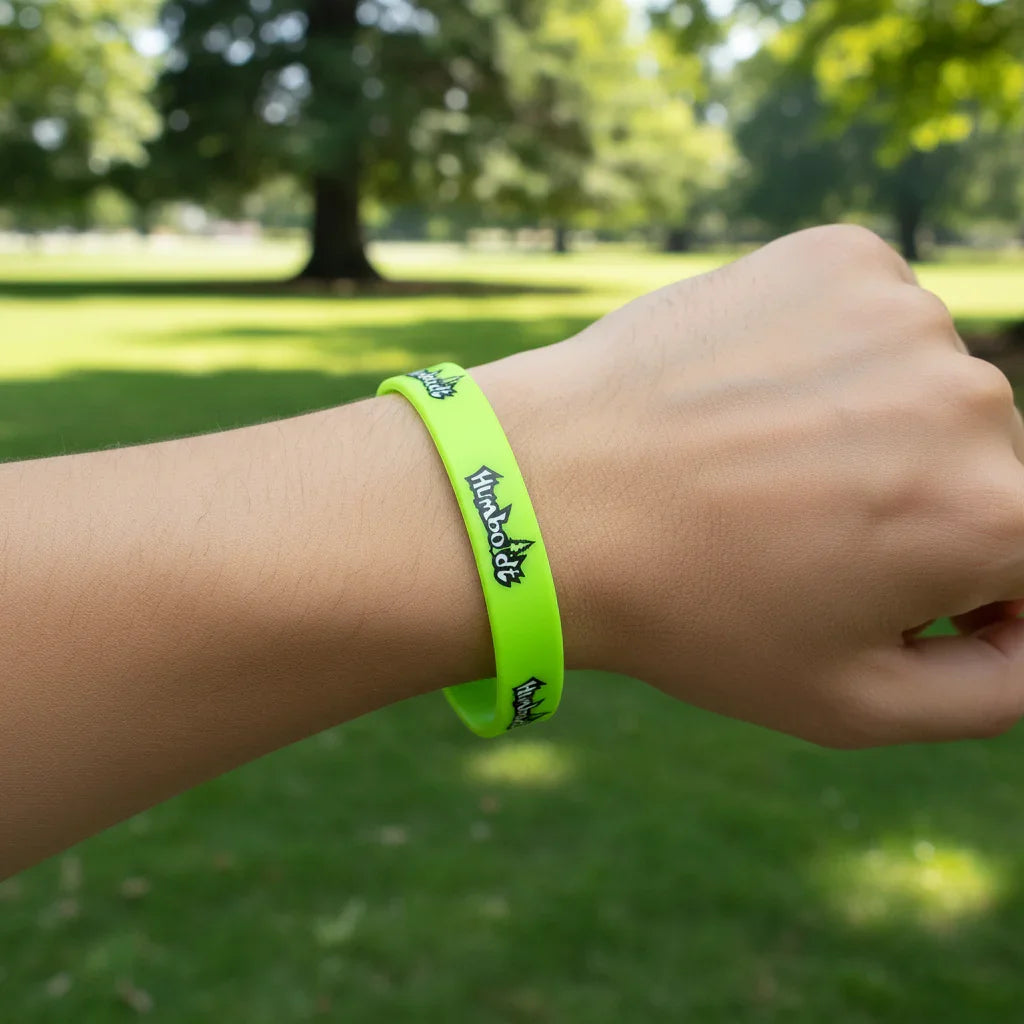 Neon green wristband with Humboldt logo, worn outdoors in a sunny park setting.